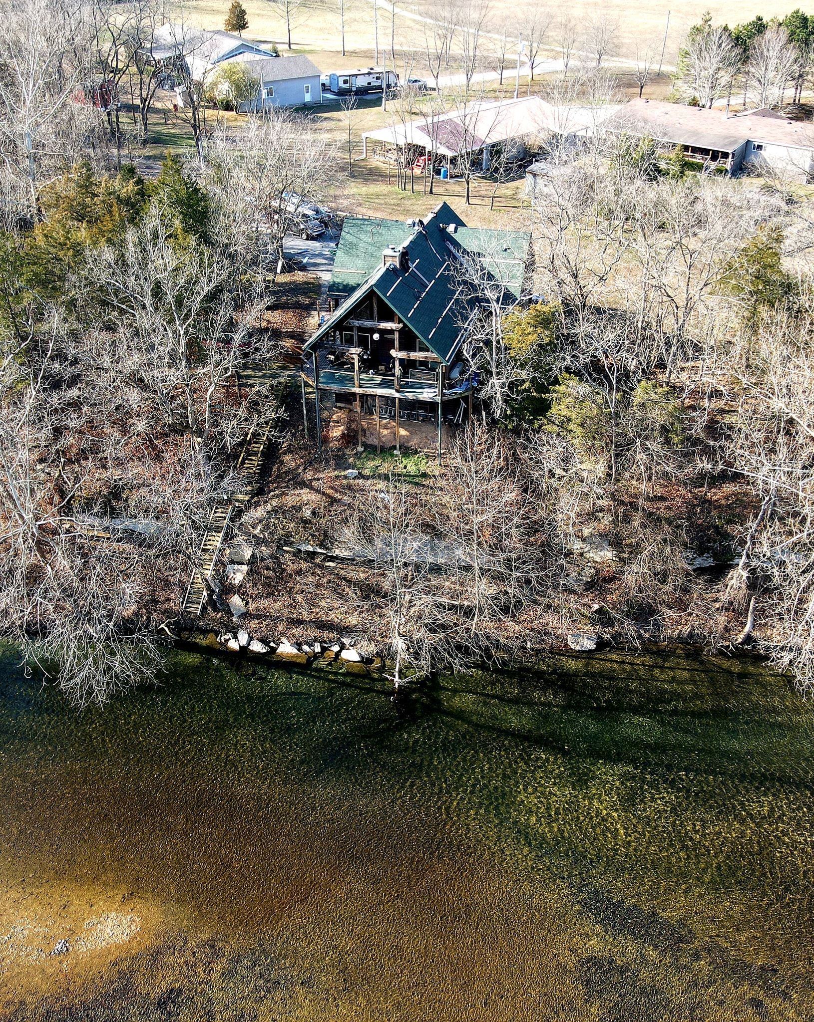 Blue-roofed cabin tucked in snowy trees beside a dark riverbank