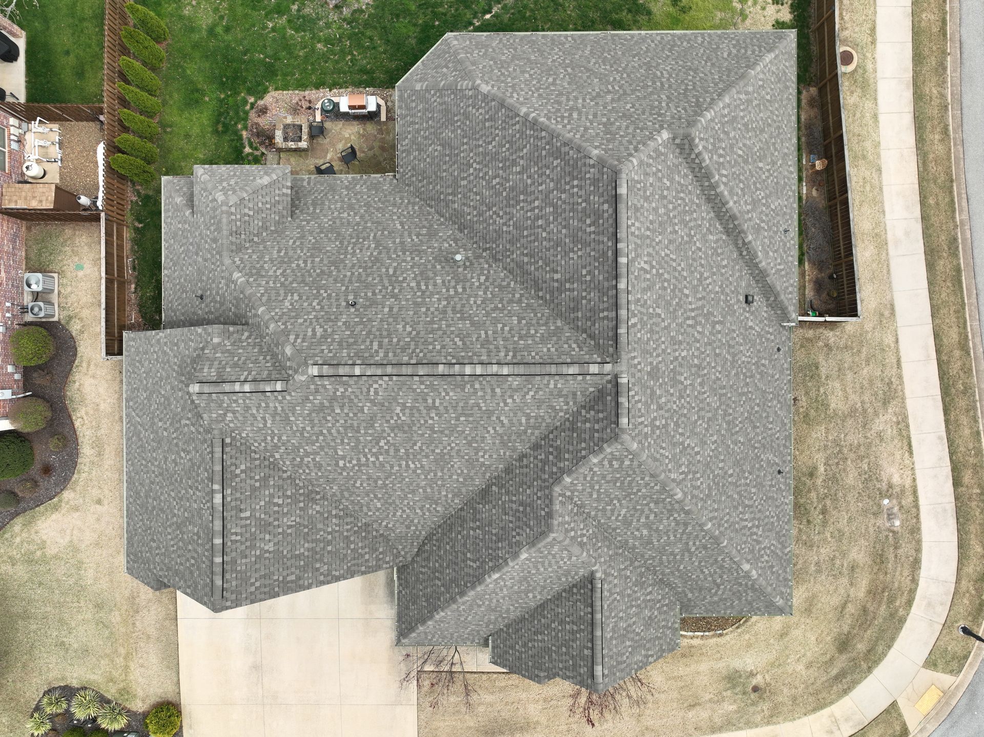 Aerial view of a gray-roofed house with driveway and surrounding yard.