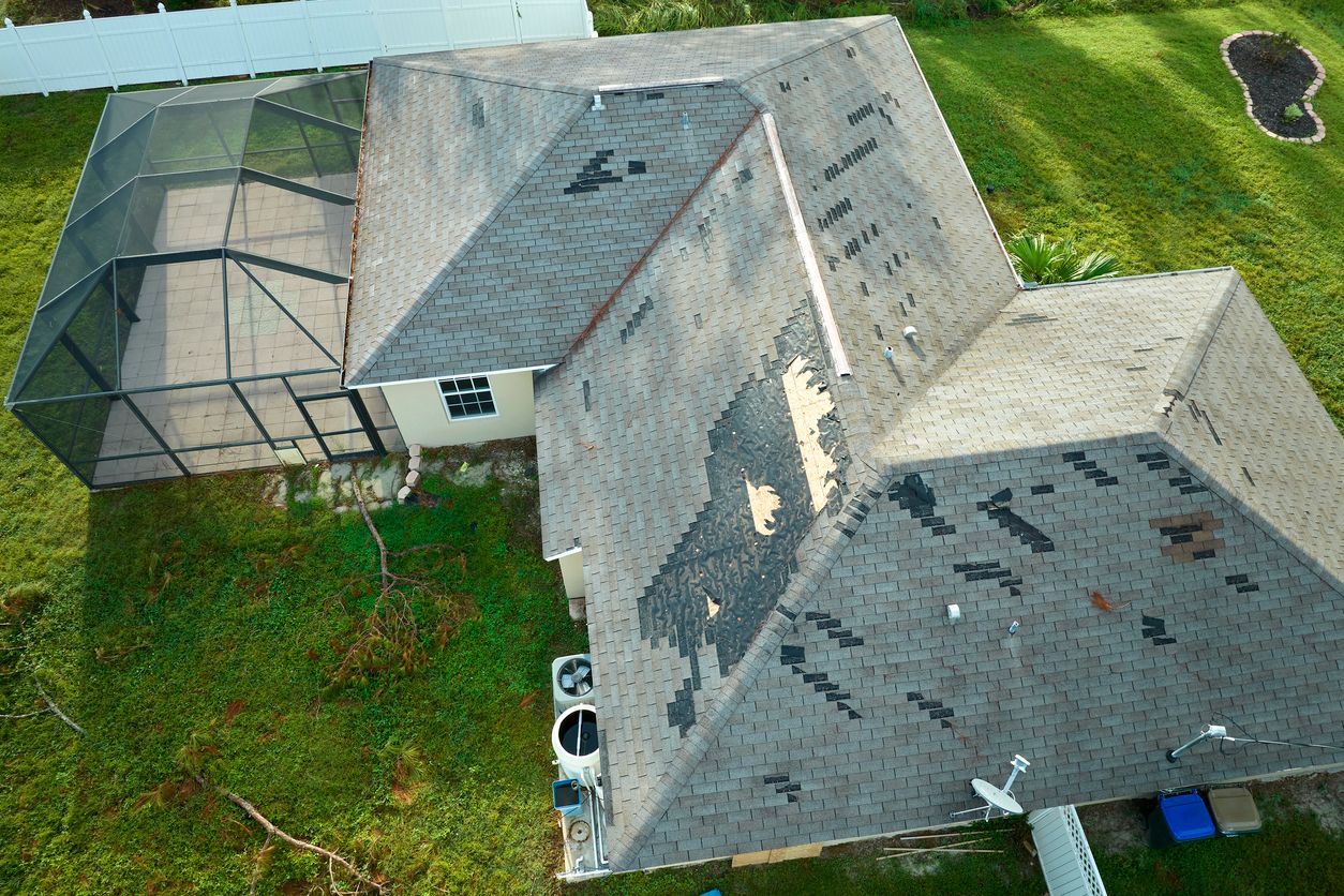 Aerial view of a gray-roofed house with a screened porch and green lawn.