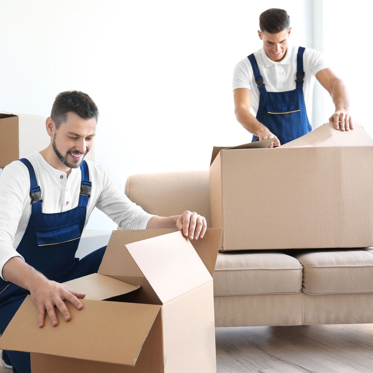 two men are packing boxes in a living room and one of the boxes has the word kitchen written on it