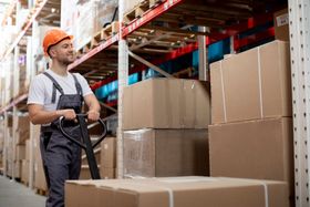 a man in a hard hat is pushing a cart full of cardboard boxes