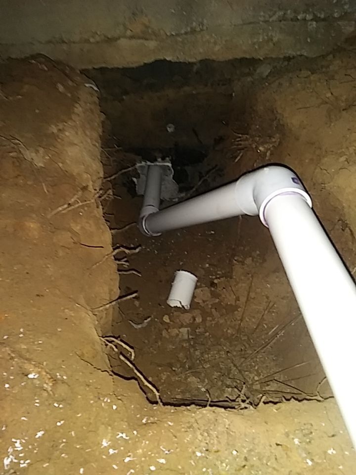 A white pipe is coming out of a hole in the ground.