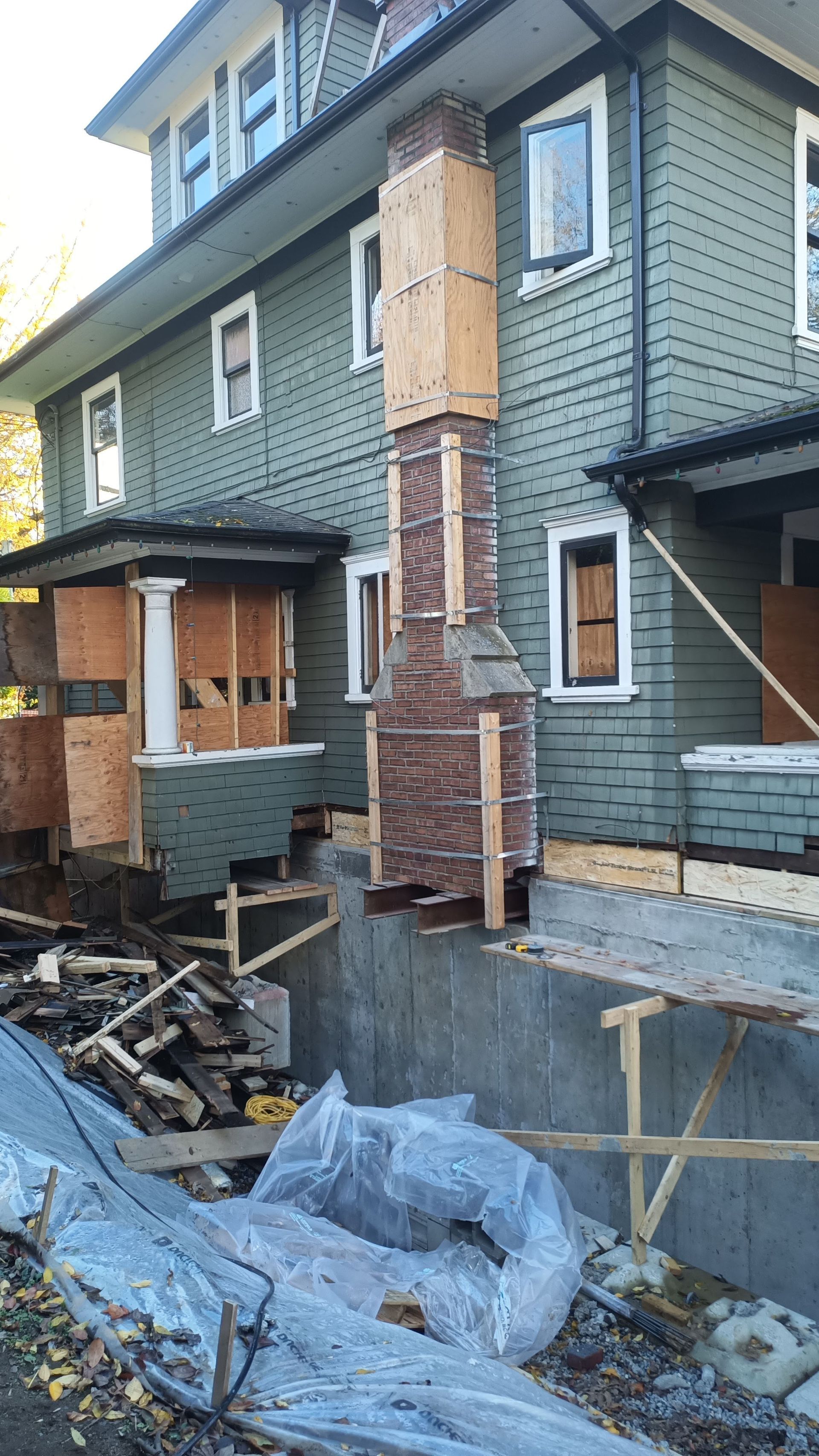 Partially built brick-and-siding house exterior with scaffolding and construction debris in front