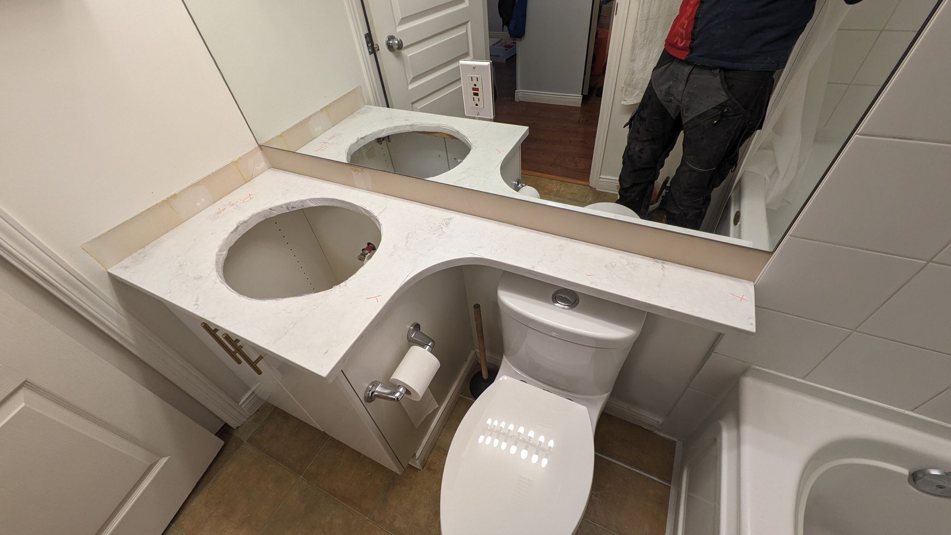Small accessible bathroom with a toilet and sink, seen in mirror reflection.