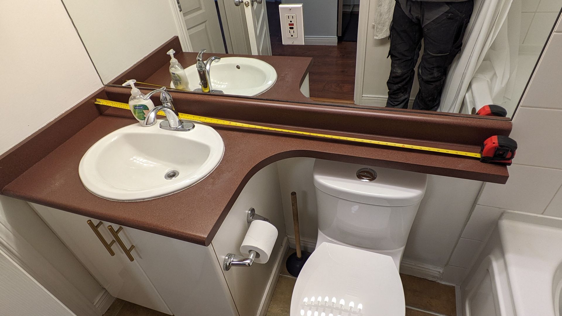 Bathroom vanity with two sinks, brown countertop, and toilet in a small restroom