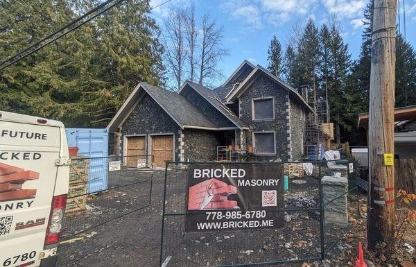 New brick house under construction with Bricked Masonry sign and work van on site