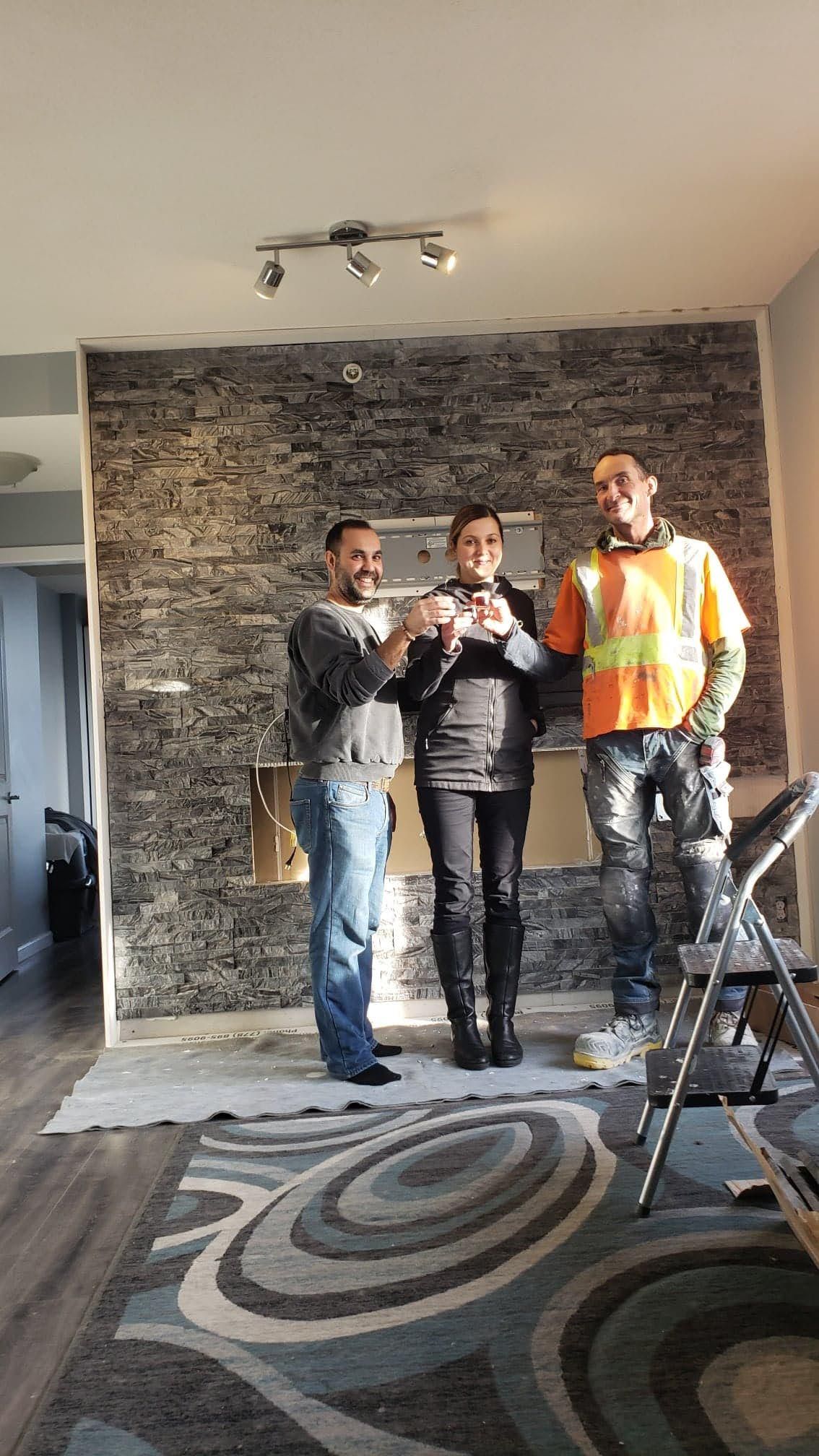 Happy home owners standing with Chris in front of their new modern fireplace.