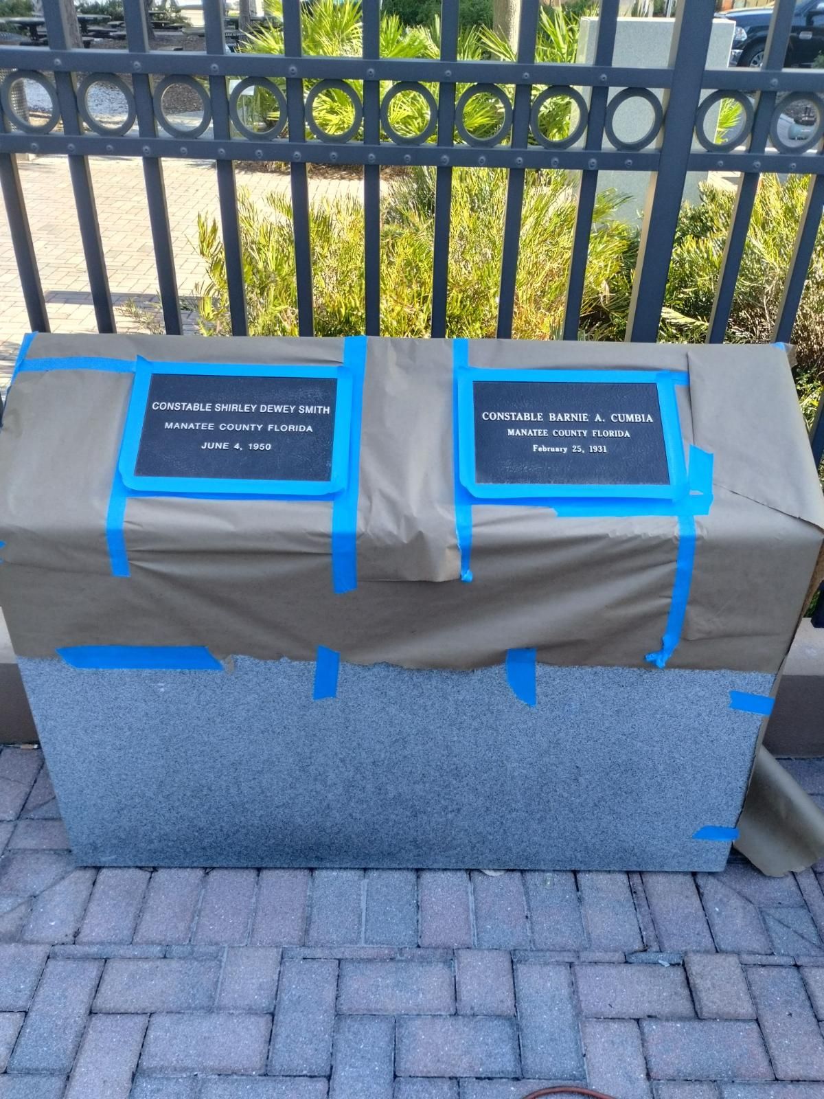 A box with two plaques taped to it is sitting on a brick sidewalk