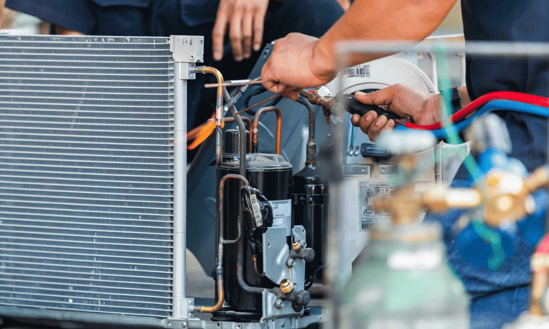 Hands repairing a car radiator with tools in a garage, with hoses and engine parts visible