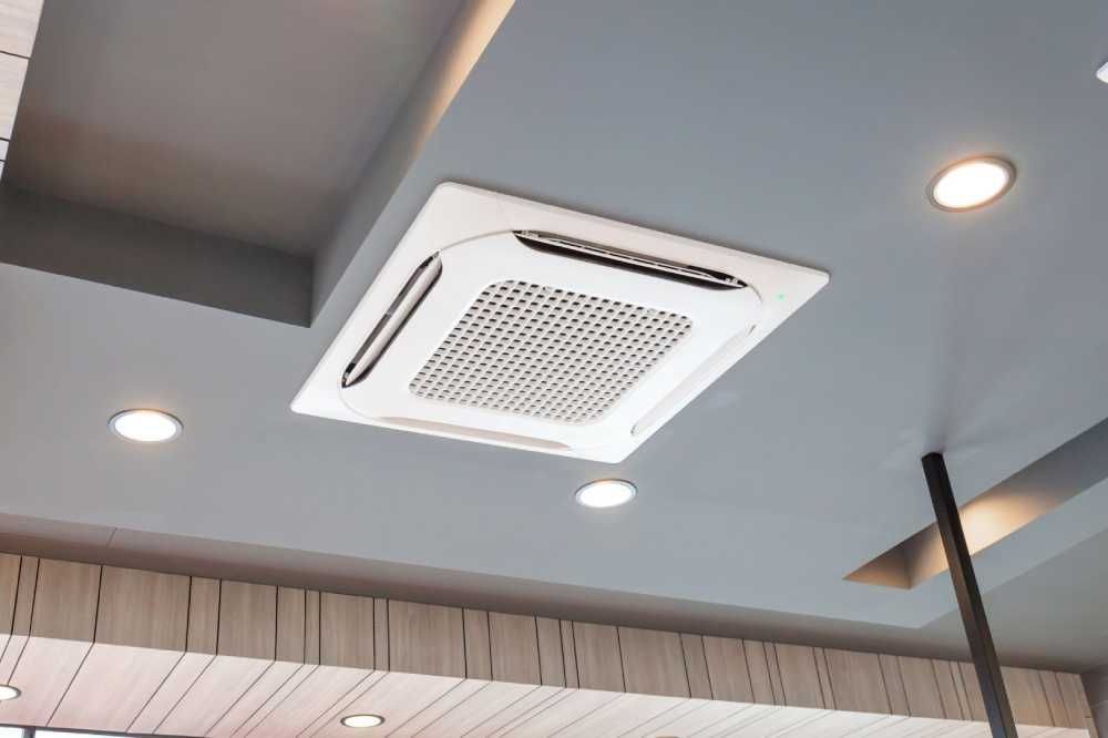 Ceiling-mounted white air conditioner with recessed lights in a modern interior with wood paneling