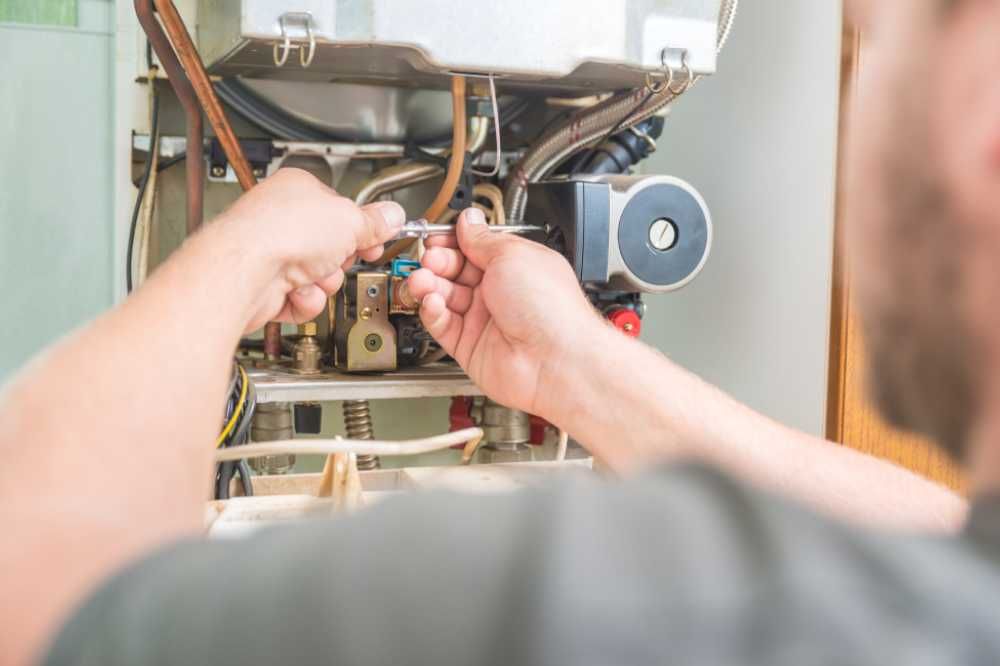 Technician adjusting wiring inside an open boiler or furnace unit