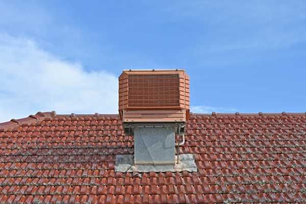 Rooftop chimney with a red tile roof under a blue sky