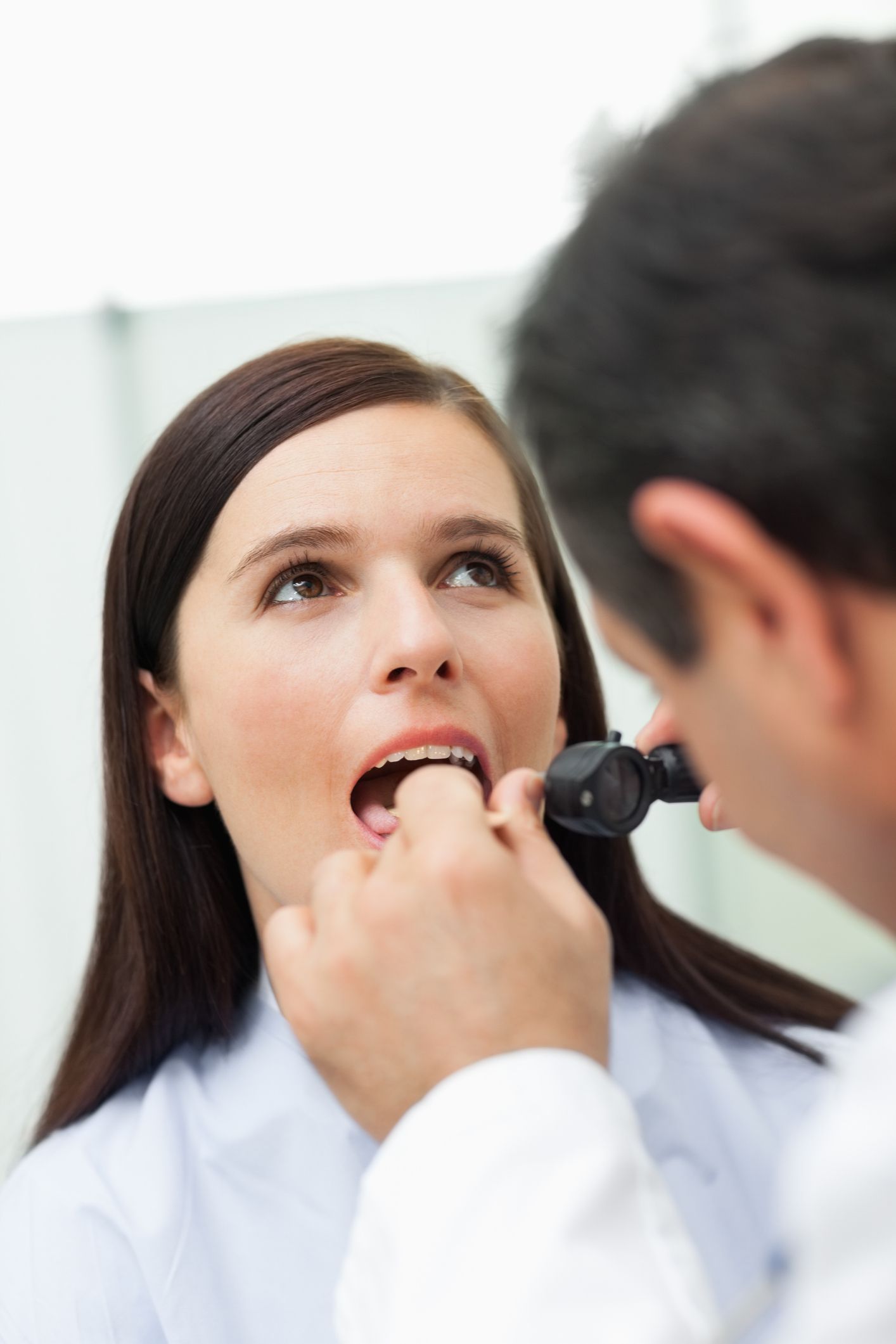 Doctor examining a patient's mouth with a light.