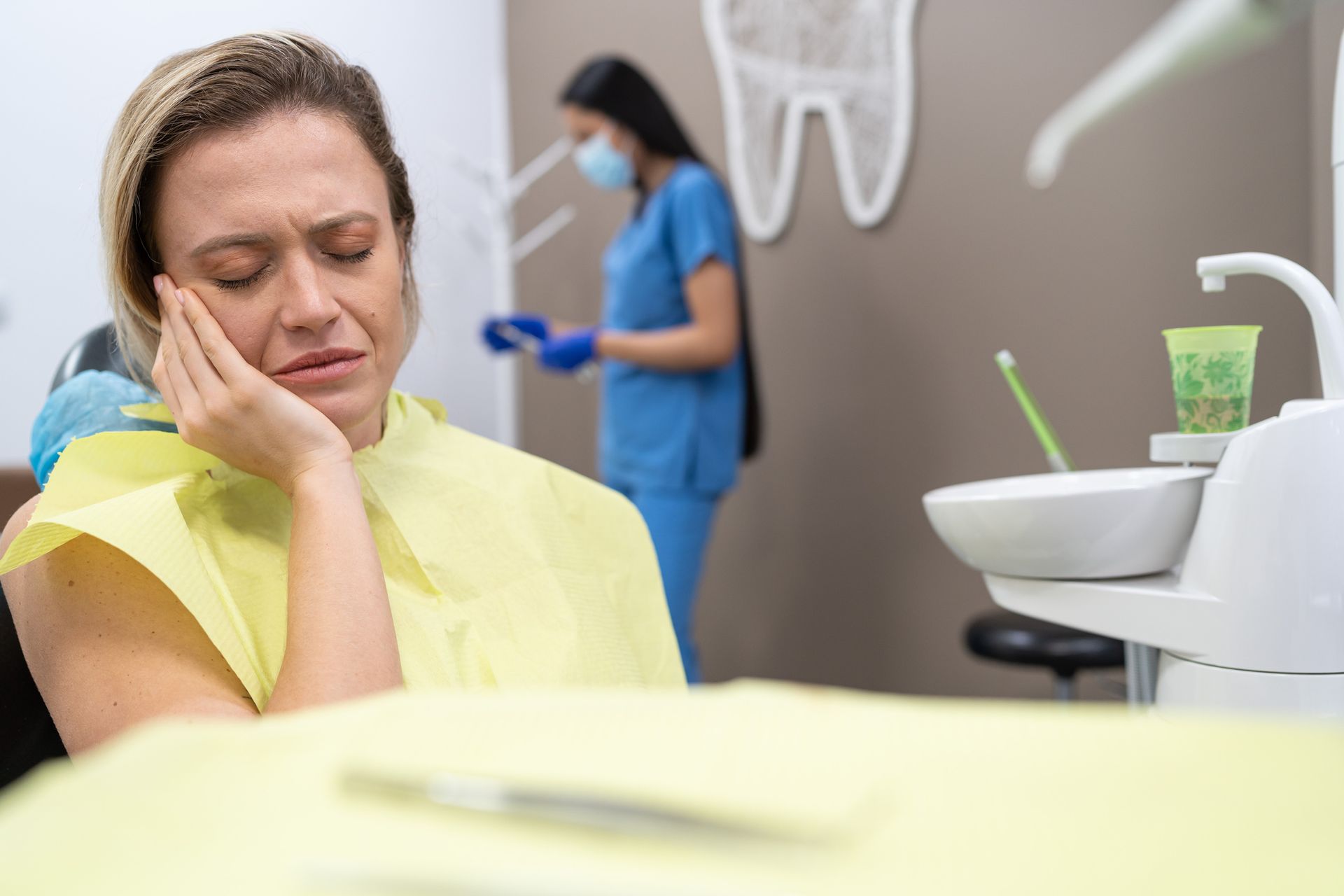 A woman is suffering from a toothache, sitting in a dental chair.