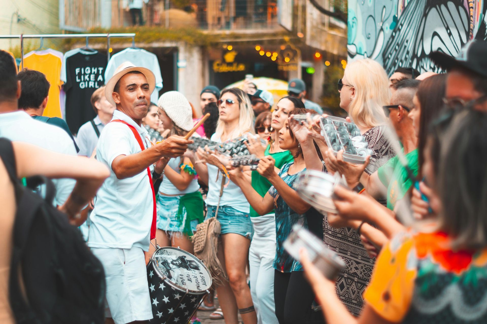 A man is playing a drum in front of a crowd of people.