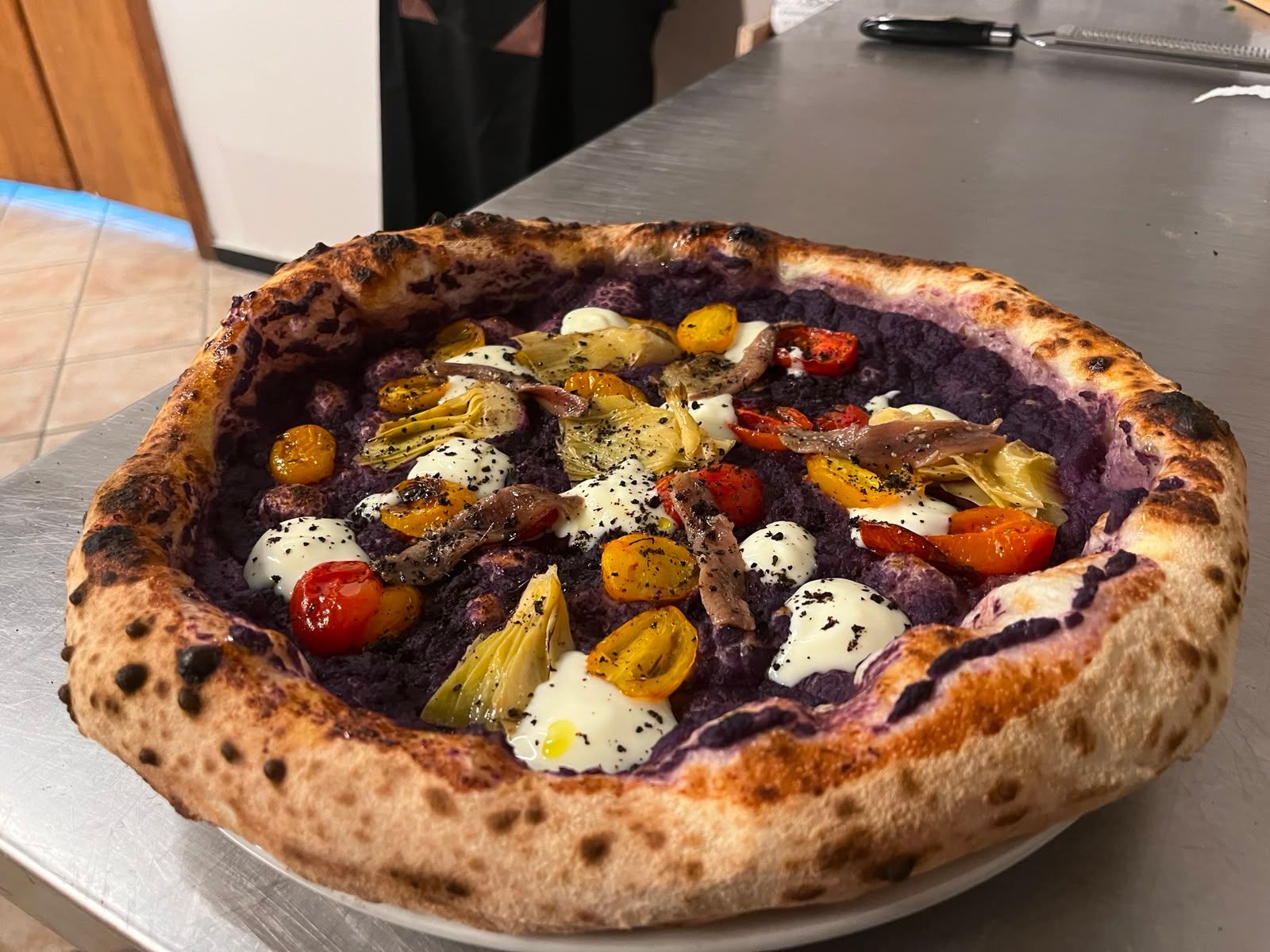 Pizza cotta nel forno a legna con verdure e erbe aromatiche arrostite su un tavolo