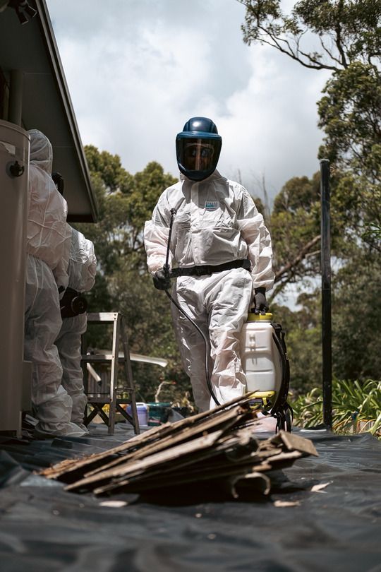 A Man in A White Suit Is Digging in The Dirt — Asbestos Risk Removal In Gladstone, QLD