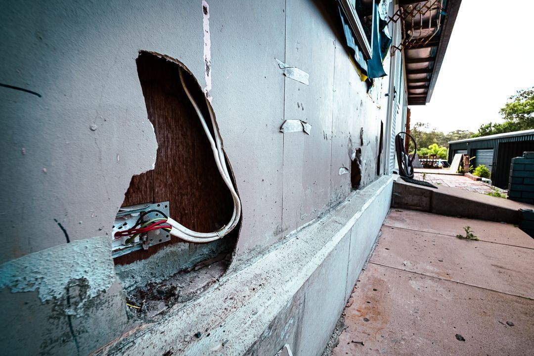 A Man in A Protective Suit Is Working on A Roof — Asbestos Risk Removal In Gladstone, QLD