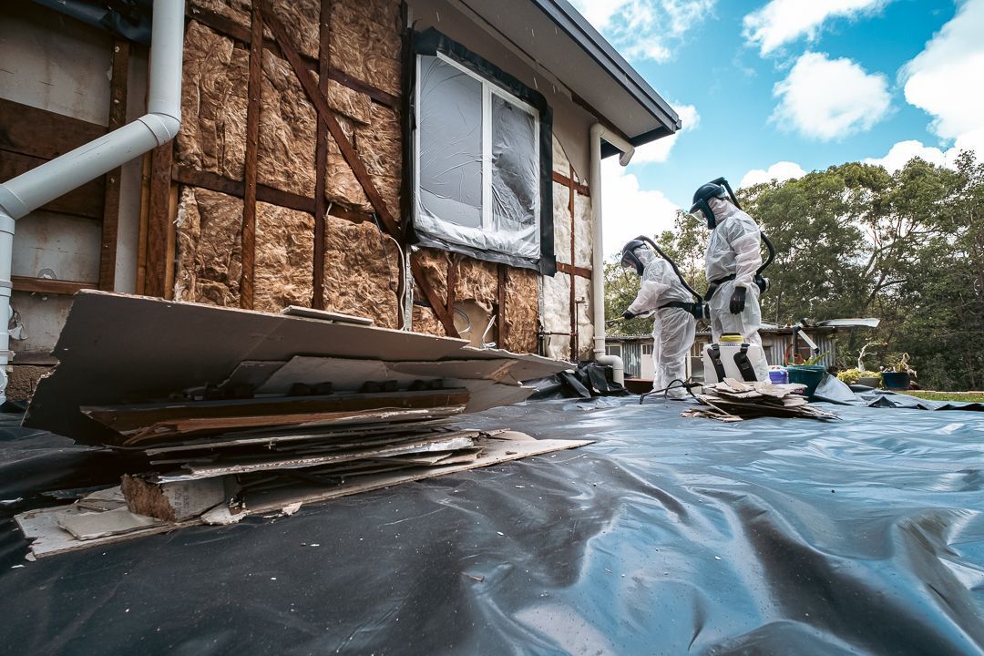 Two Men in Protective Suits Are Working on A Roof — Asbestos Risk Removal In Gladstone, QLD