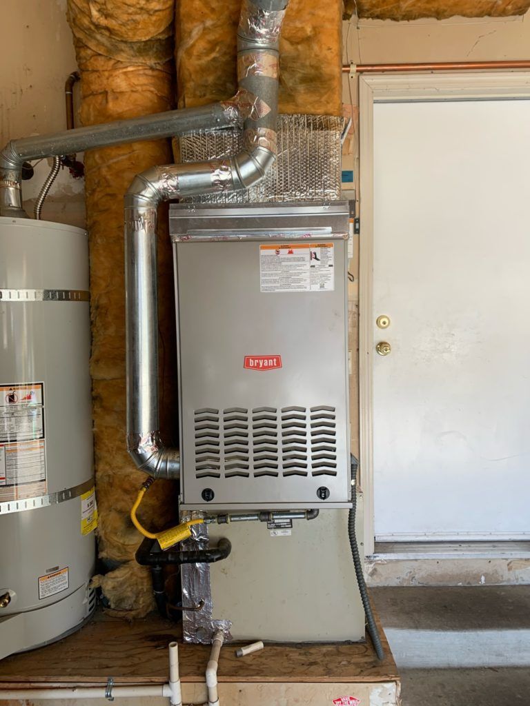 Water heater and furnace with vent pipes near a white door.