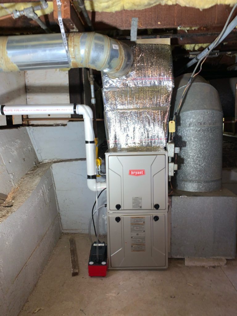 Furnace and ductwork in a basement. Silver metal, gray concrete walls, red safety switch.