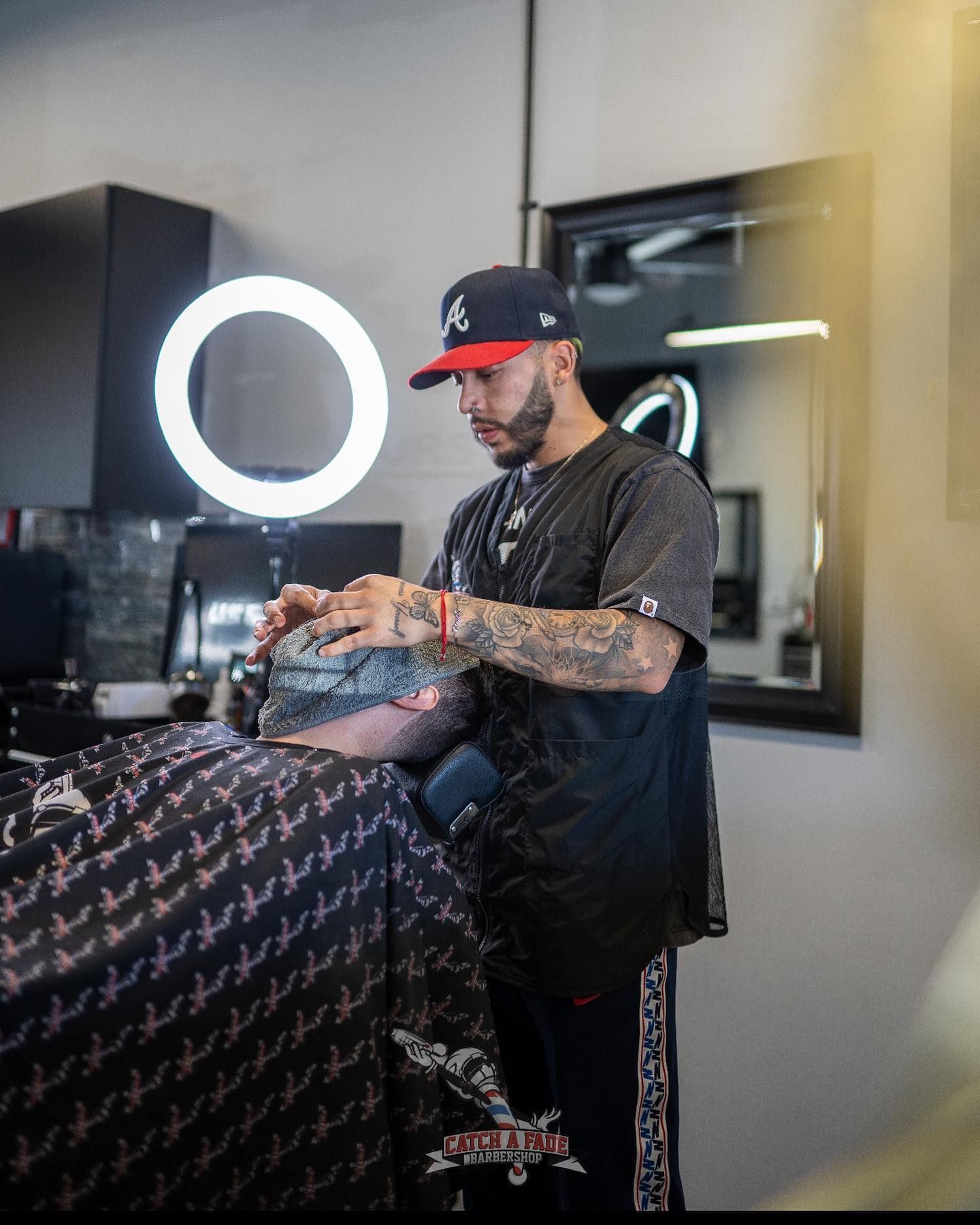Barber wearing a hat cutting a client's hair in a salon. 