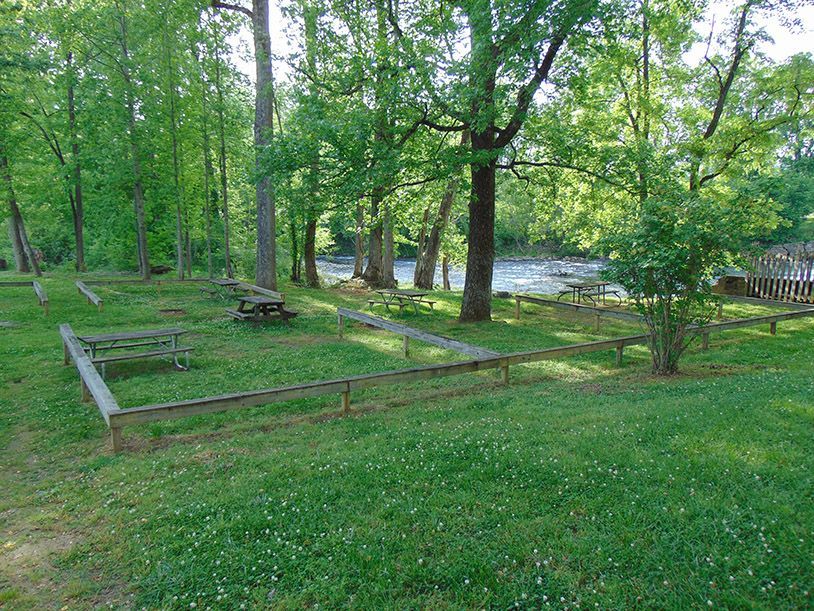 A picnic area with a wooden fence and a river in the background.