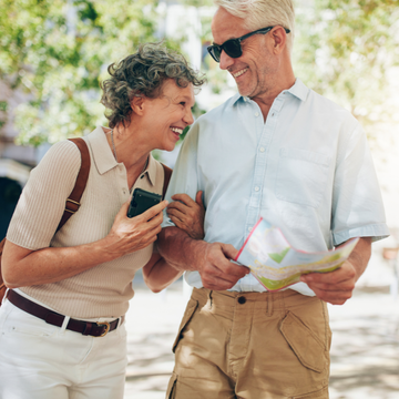 Two smiling people looking at a map outdoors, one holding a phone.