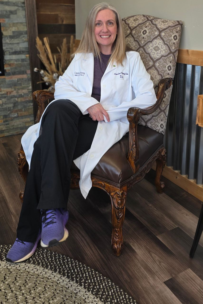 Candace Herrin, APRN, FNP-C sits in a chair smiling.