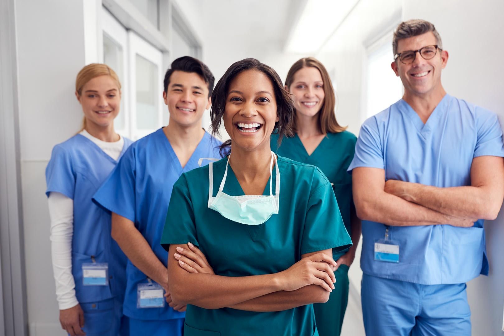 A group of doctors and nurses are posing for a picture in a hospital hallway.