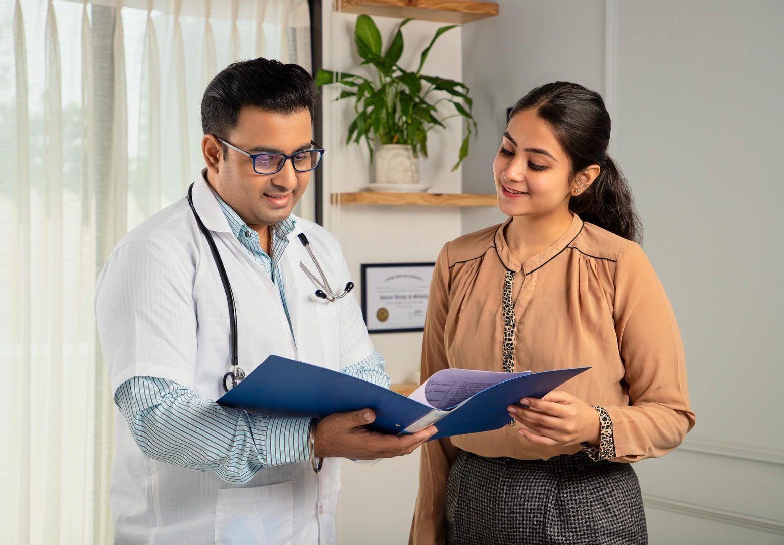 A doctor is talking to a patient while holding a clipboard.