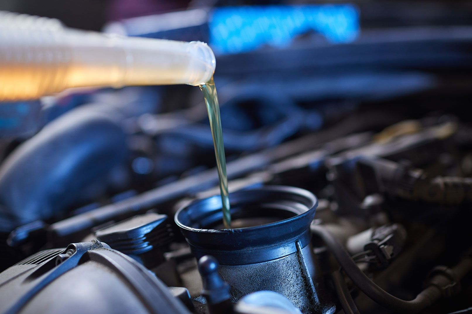 Pouring motor oil into a car engine under the hood