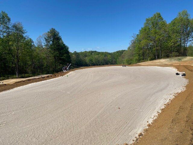 Newly paved curved road through a wooded area under a clear blue sky
