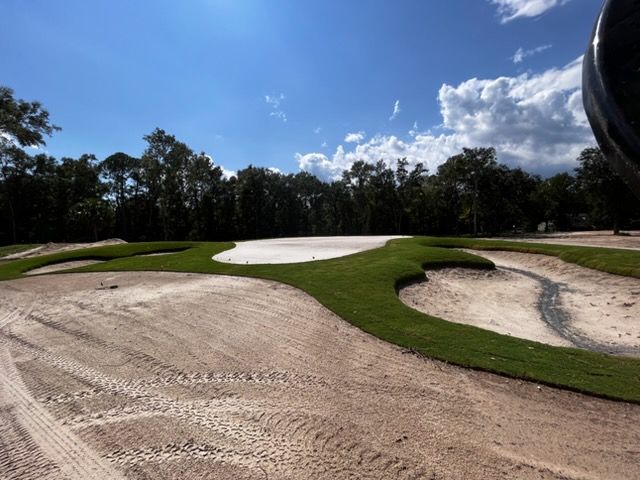 Golf course sand bunkers and green fairways under a blue sky with clouds