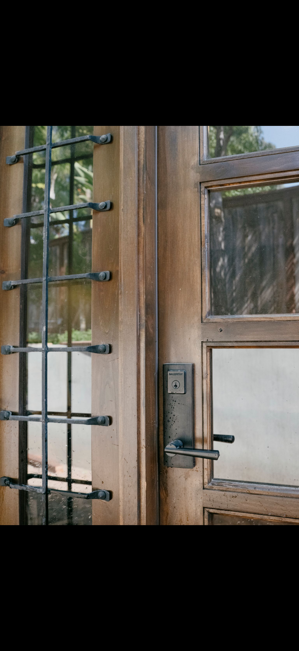 Wooden door with metal bars and a handle, showing part of a window on the right.