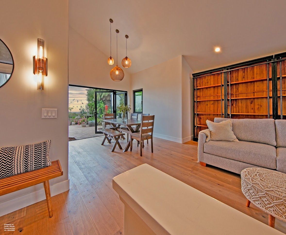 Dining area with table, chairs, and sliding doors opening to a garden. Light wood floors and neutral walls.