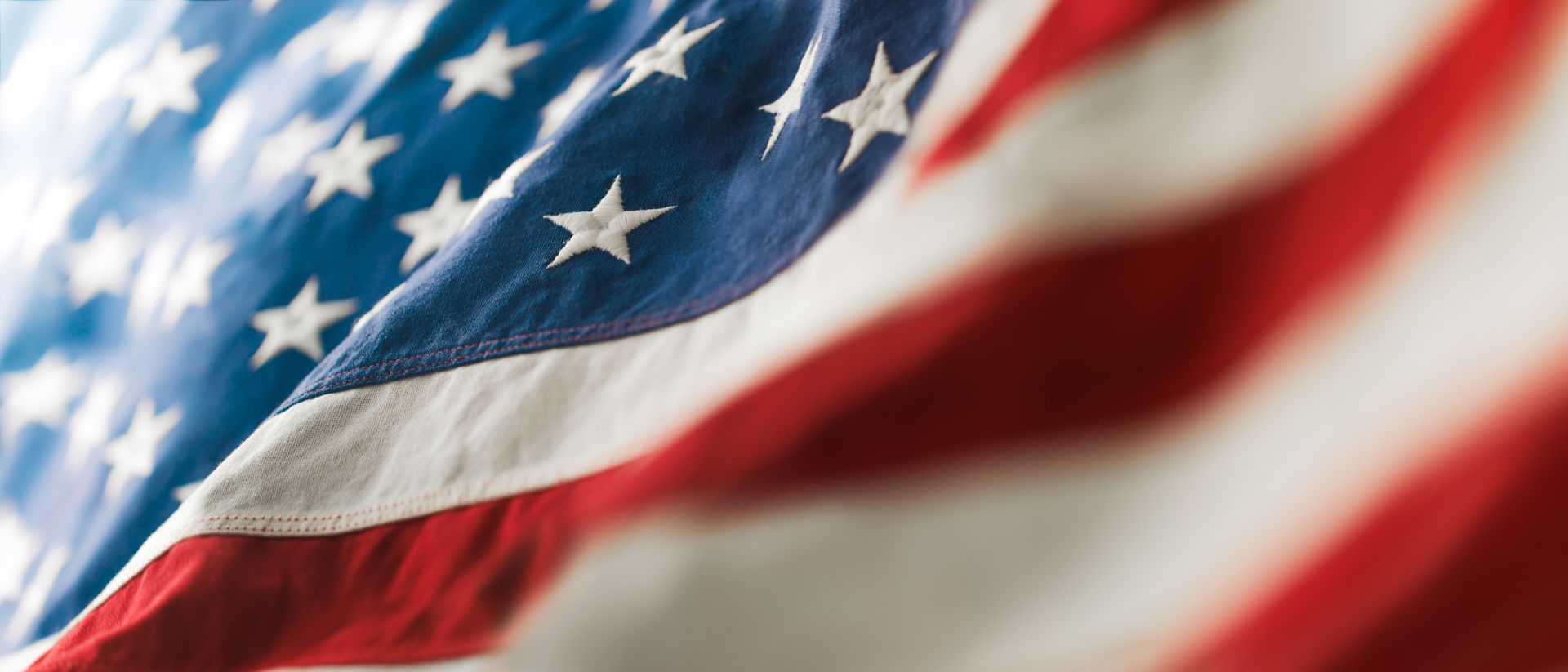 American flag waving, stars and stripes detail. Blue field with white stars and red and white stripes.
