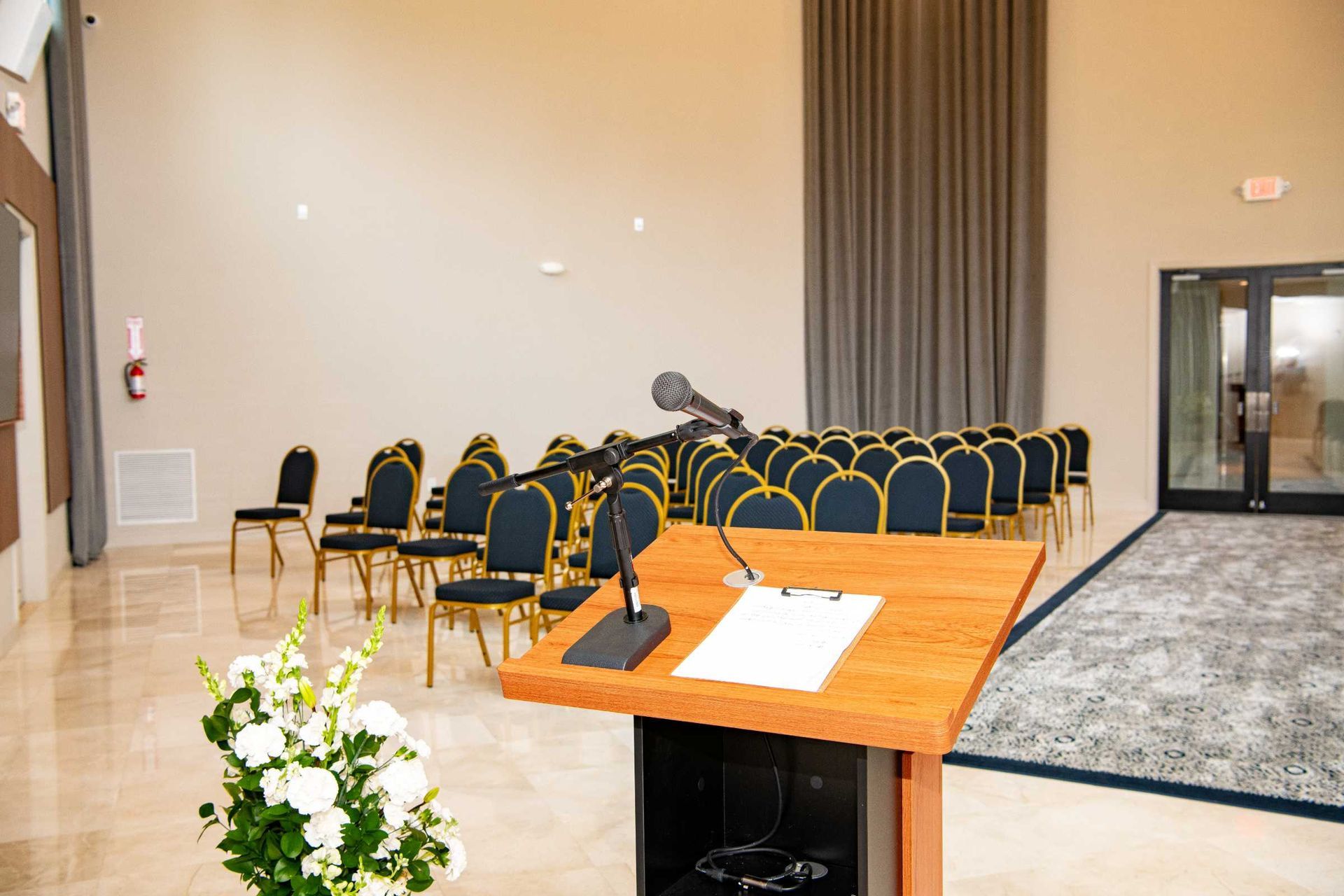 Lecture hall with rows of black chairs, a podium, and a microphone on a stage area