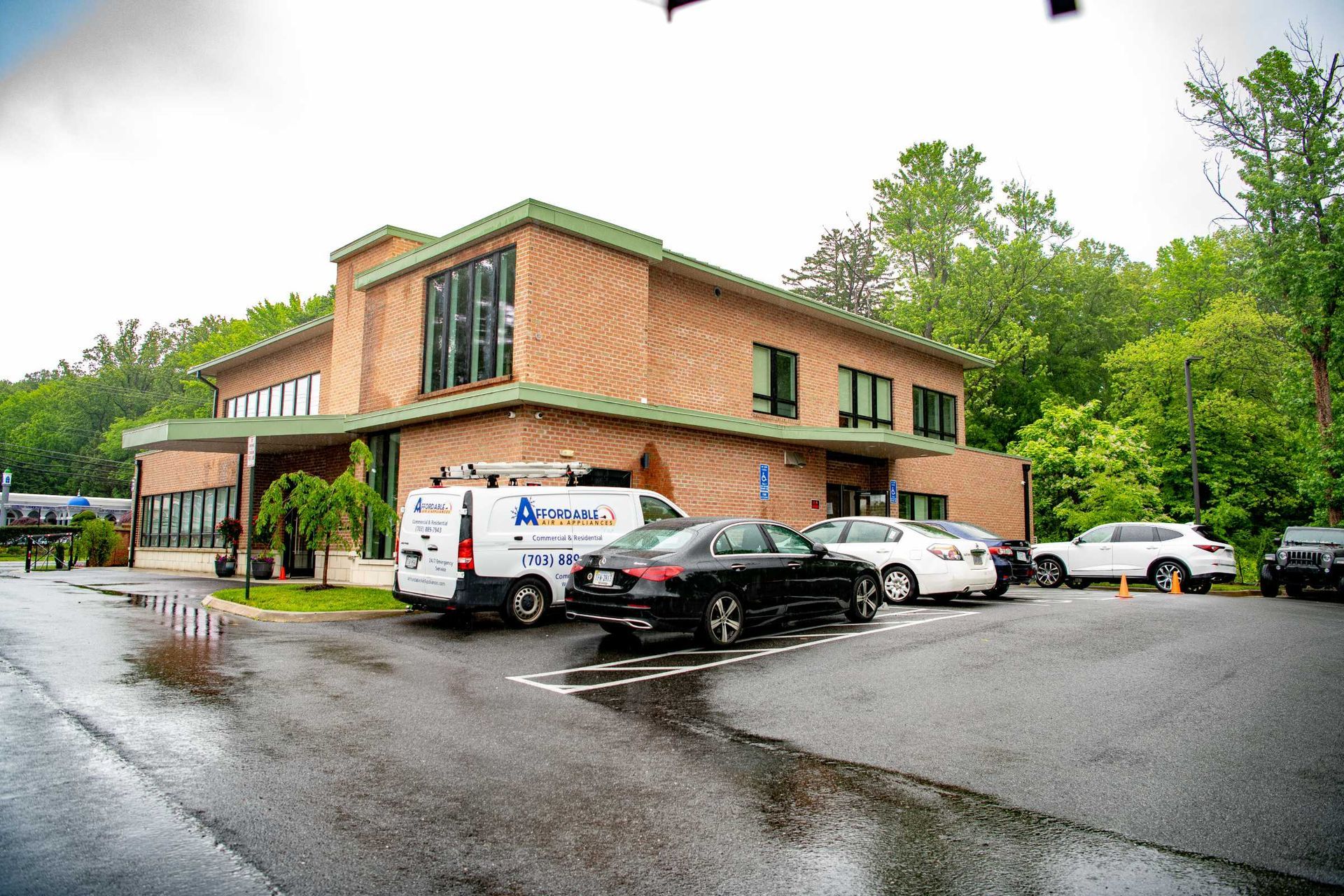 Brick office building with parked cars and vans on a wet rainy day