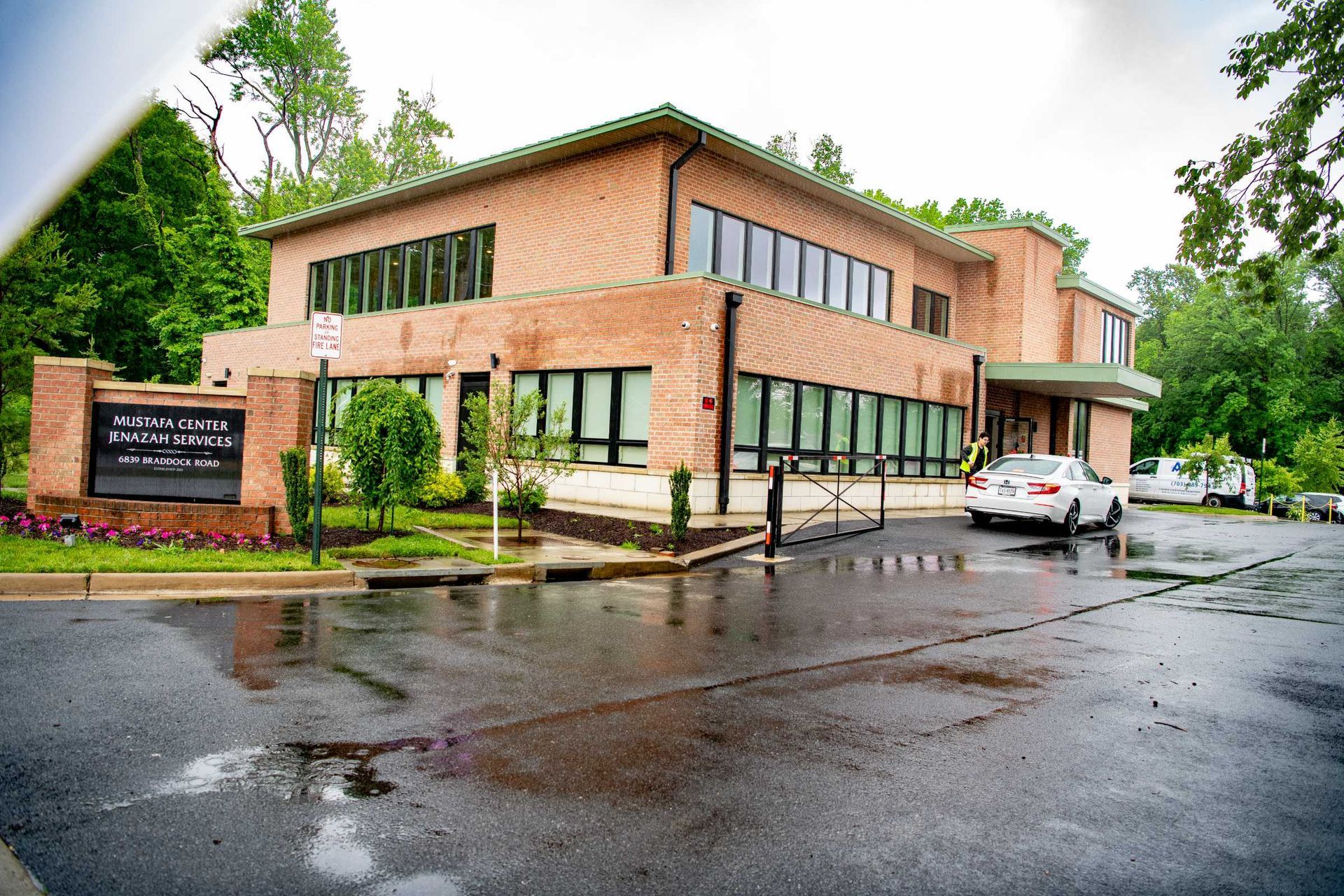 Brick office building on a rainy day with parked cars and wet pavement