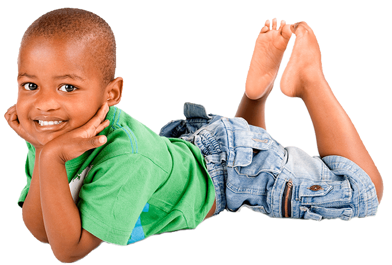 A young boy is laying on his stomach with his head resting on his hands