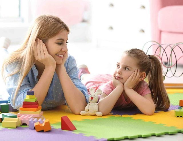 A woman sitting at a table with a young boy playing with wooden blocks 