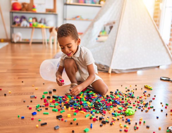 A young boy sitting on the floor playing with Lego blocks