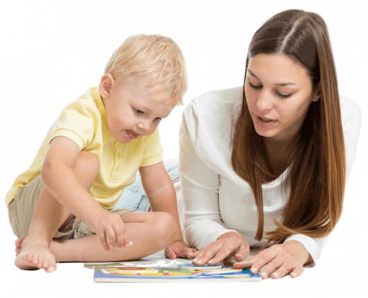 A woman and a child sitting on the floor reading a book 
