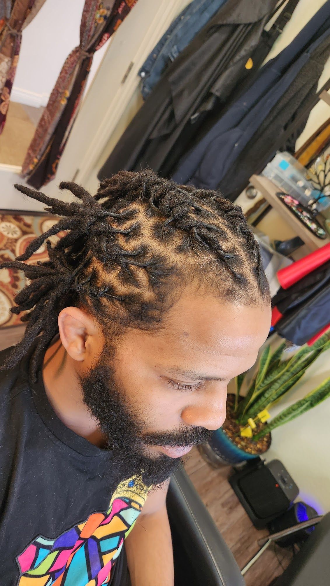 A man with dreadlocks and a beard is sitting in a chair in a room.