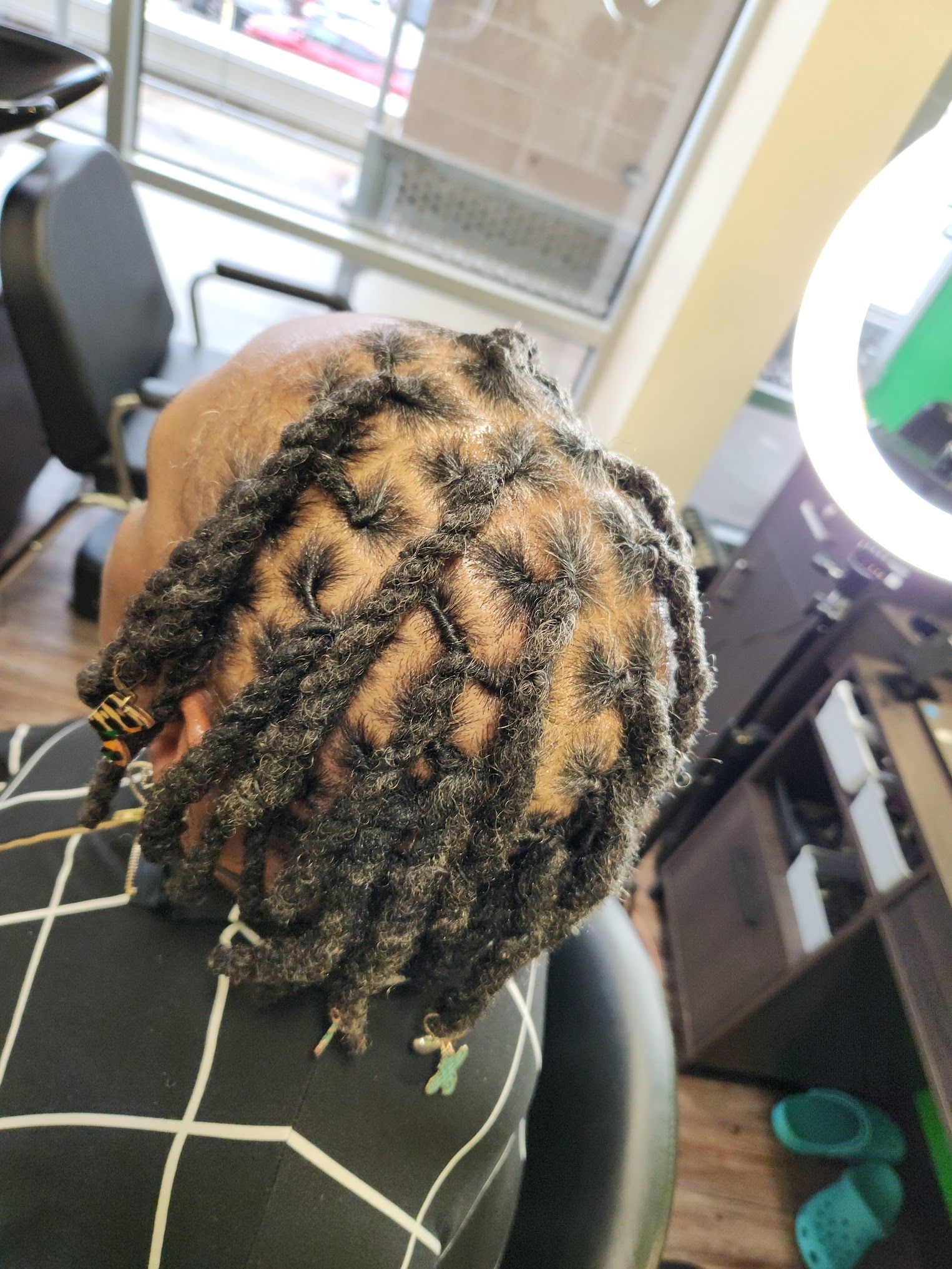 A woman with dreadlocks is sitting in a chair in a salon.