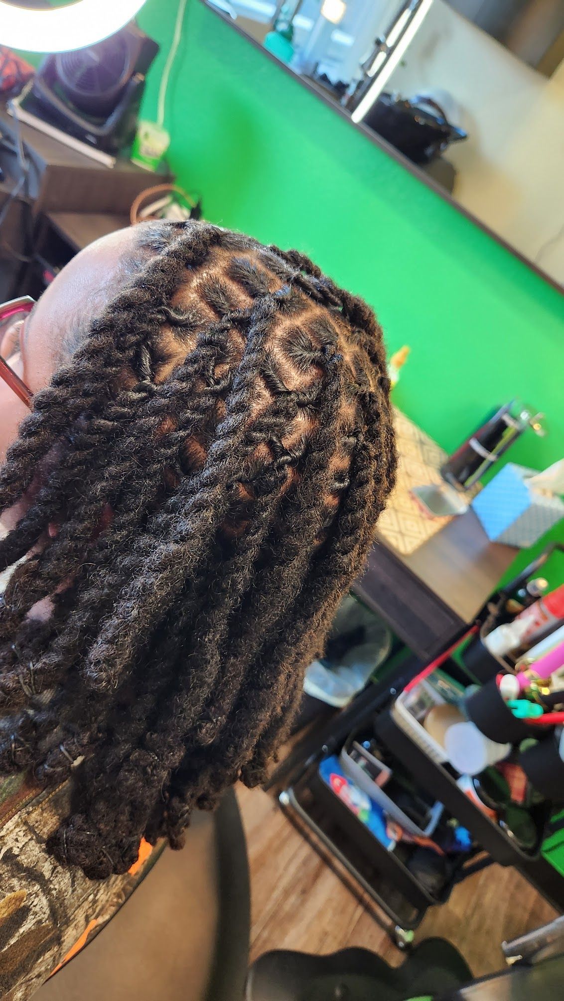 A woman is getting her hair braided in a salon.