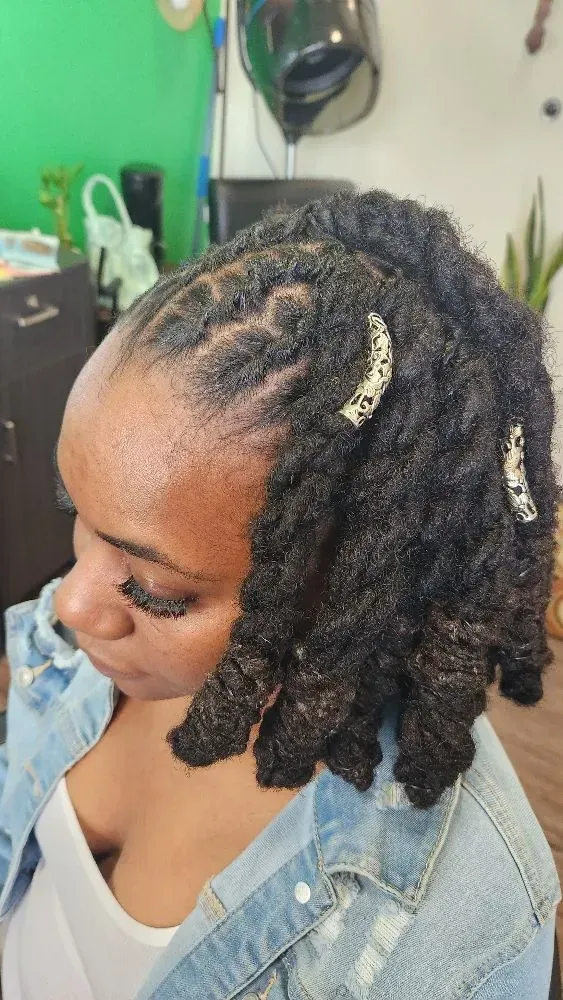 A woman with dreadlocks is wearing a denim jacket.