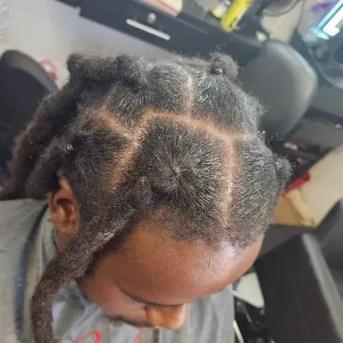 A man with dreadlocks is sitting in a chair in a salon.