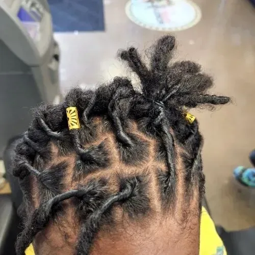 A close up of a person 's head with dreadlocks and yellow beads.